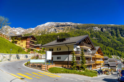 Houses and road by buildings against clear blue sky