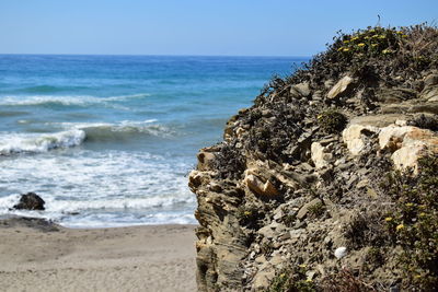 Rock at beach against clear sky