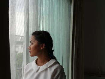Close-up of young woman looking through window