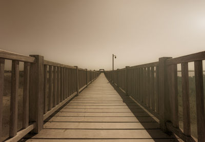 View of wooden footbridge against clear sky