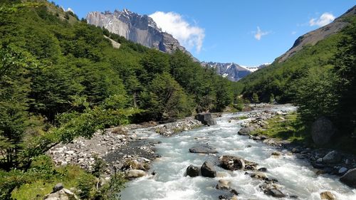 Scenic view of river flowing amidst mountains against sky