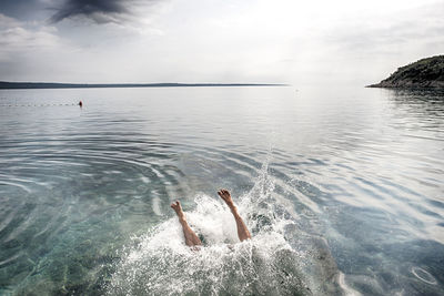 High angle view of woman drowning in sea against sky