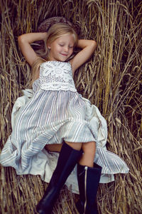 Blonde girl lying on the field among the dry ears of wheat in the summer