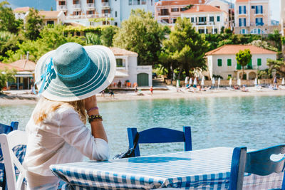 Side view of woman sitting at table against sea