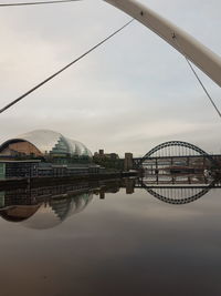 Bridge over river in city against sky