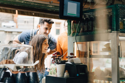 Smiling friends looking at food while standing by concession stand in city