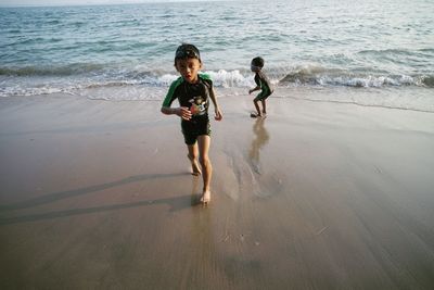 Full length portrait of boy with brother at beach