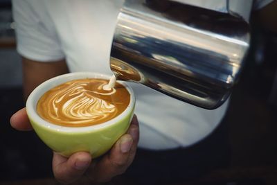 Midsection of man making pattern on drink