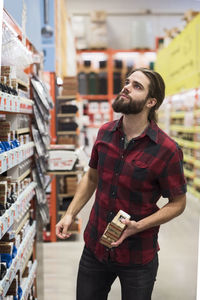 Male customer holding nail boxes from hardware store