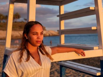 Portrait of young woman standing by railing against sea
