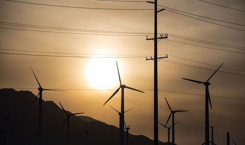 Low angle view of silhouette cables against sky during sunset