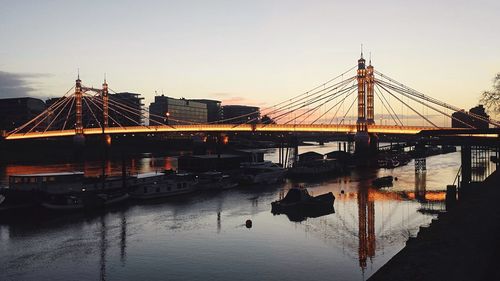 Silhouette bridge over river against sky during sunset