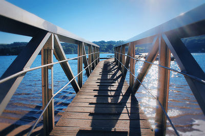 Footbridge over sea against clear blue sky