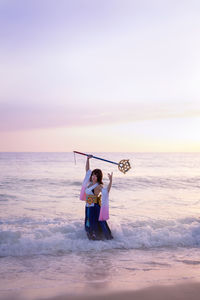 Young woman holding wand at beach during sunset