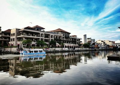 Buildings by lake against sky in city