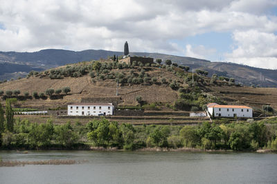 Built structure by lake and buildings against sky