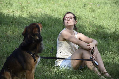 Portrait of a young woman with dog on field