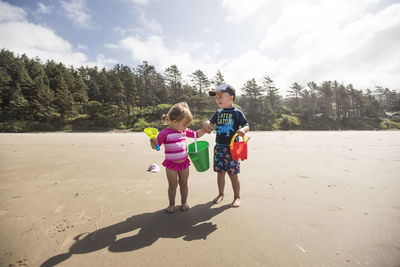 Brother and sister playing at the beach on a windy day.