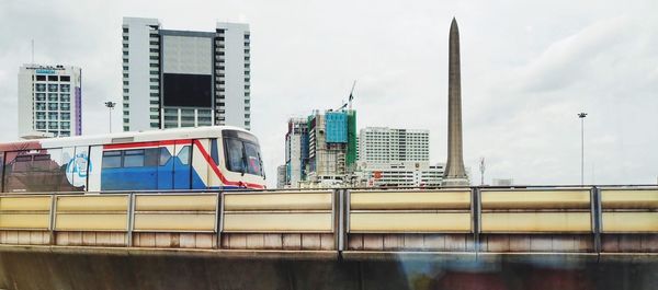 Modern buildings by river against sky in city