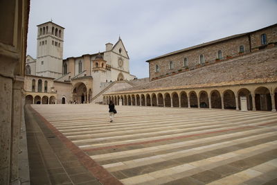 Woman walking outside historic building against sky