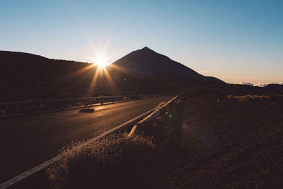 Road by mountains against sky during sunset