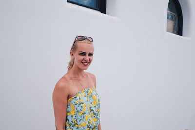 Portrait of smiling young woman standing against wall