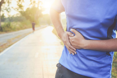 Midsection of man with stomachache standing on road