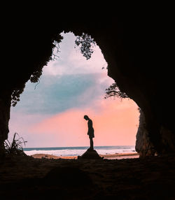 Silhouette man standing on beach against sky during sunset