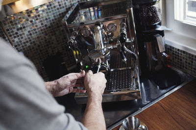 Cropped image of hand holding coffee filter using espresso maker at home