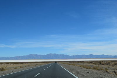 Road by landscape against blue sky