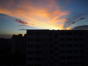 Silhouette of building against cloudy sky at sunset