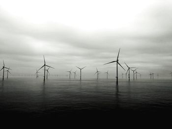 Wind turbines on sea against sky
