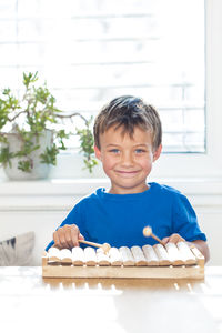 Portrait of smiling boy playing xylophone on table