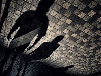 Low section of man shadow on tiled floor