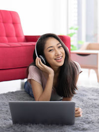 Young woman using phone while sitting on sofa at home