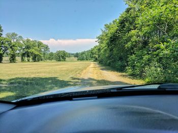 Road amidst trees against sky seen through car windshield