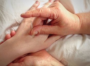 Close-up of woman giving acupuncture to customer on bed