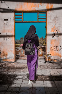 Rear view of woman standing against graffiti wall