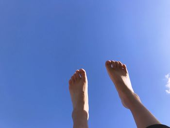 Low angle view of legs against blue sky