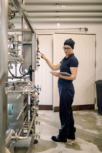 Farmer using digital tablet pc and operating machine at dairy factory