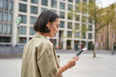 Young woman using mobile phone in city