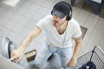 High angle view of young university student listening music while doing laundry