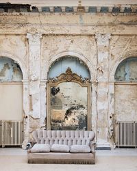 Empty sofa against wall in old abandoned room