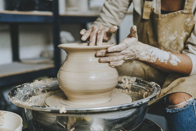 Hands of craftswoman molding pot shape on pottery wheel