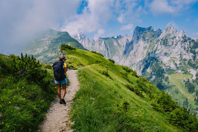 Rear view of woman walking on trail against mountain range