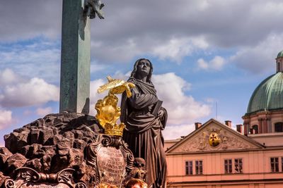 Statue of statues against building against sky