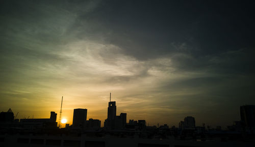 Silhouette of buildings against cloudy sky