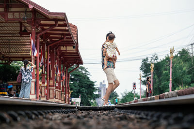 Rear view of woman with umbrella on railway bridge against sky