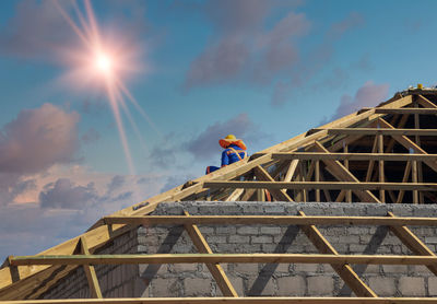 Low angle view of man working at construction site against sky