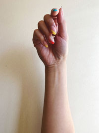 Close-up of person holding hand against wall